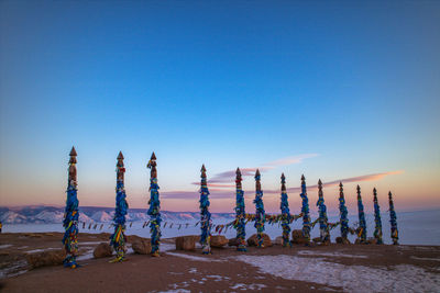 Multi colored prayer flags on bamboo poles at mountain against sky during sunset