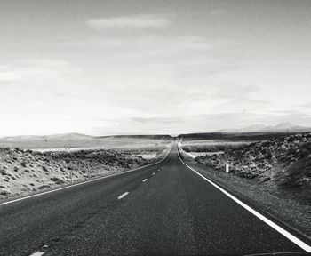 Road leading towards landscape against sky