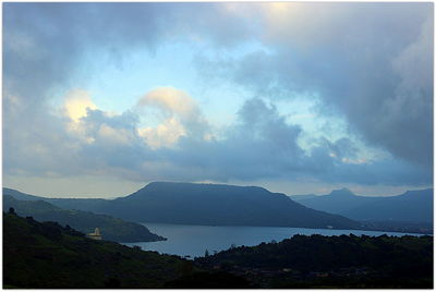 Scenic view of lake and mountains against storm clouds