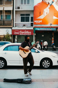 Full length of man standing on car in city