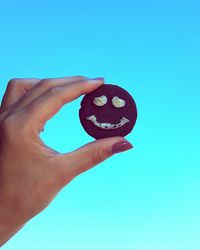 Cropped image of hand holding funny cookie