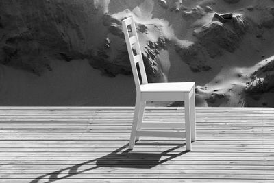 Empty chairs by swimming pool against sea