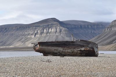 Abandoned boat on shore against sky