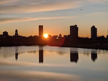 Reflection of buildings in city at sunset