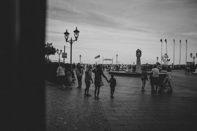 People walking on sidewalk in city during rainy season