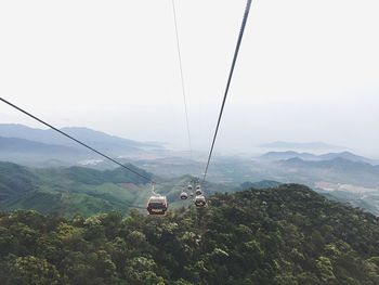 Overhead cable car over mountains against sky