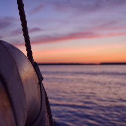 Close-up of boat on sea against sky during sunset