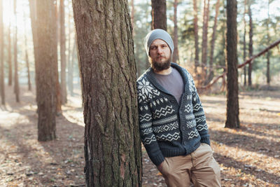 Thoughtful young man standing in forest