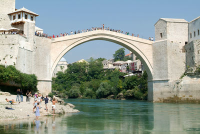 People in front of arch bridge against clear sky