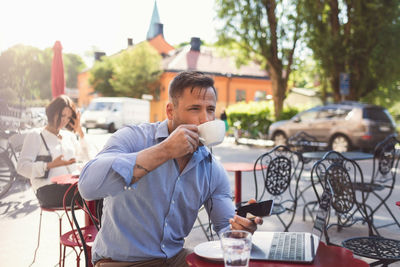 Businessman drinking coffee at sidewalk cafe