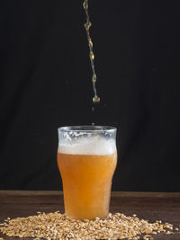 Close-up of beer glass on table against black background