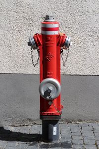 Fire hydrant on sidewalk against wall