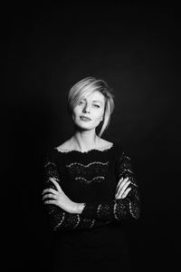 Portrait of woman standing against black background