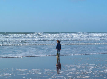 Rear view of man on beach against sky