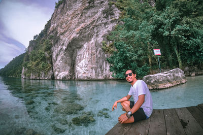 Young man sitting on rock by sea