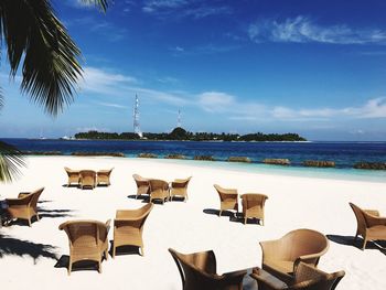 Chairs on beach by sea against sky