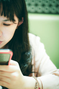 Close-up portrait of woman holding mobile phone