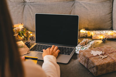 Close up woman hands, credit card, gifts, and mock up screen laptop. online shopping christmas