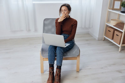 Young woman using laptop while sitting on sofa at home