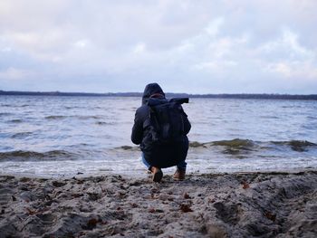 Rear view of man on beach against sky