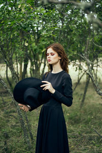 Young woman standing against trees