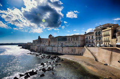 Buildings by sea against sky