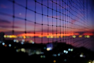 Defocused image of illuminated lights against sky at sunset