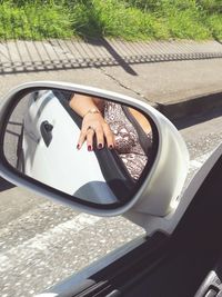 Close-up of hand on side-view mirror of car