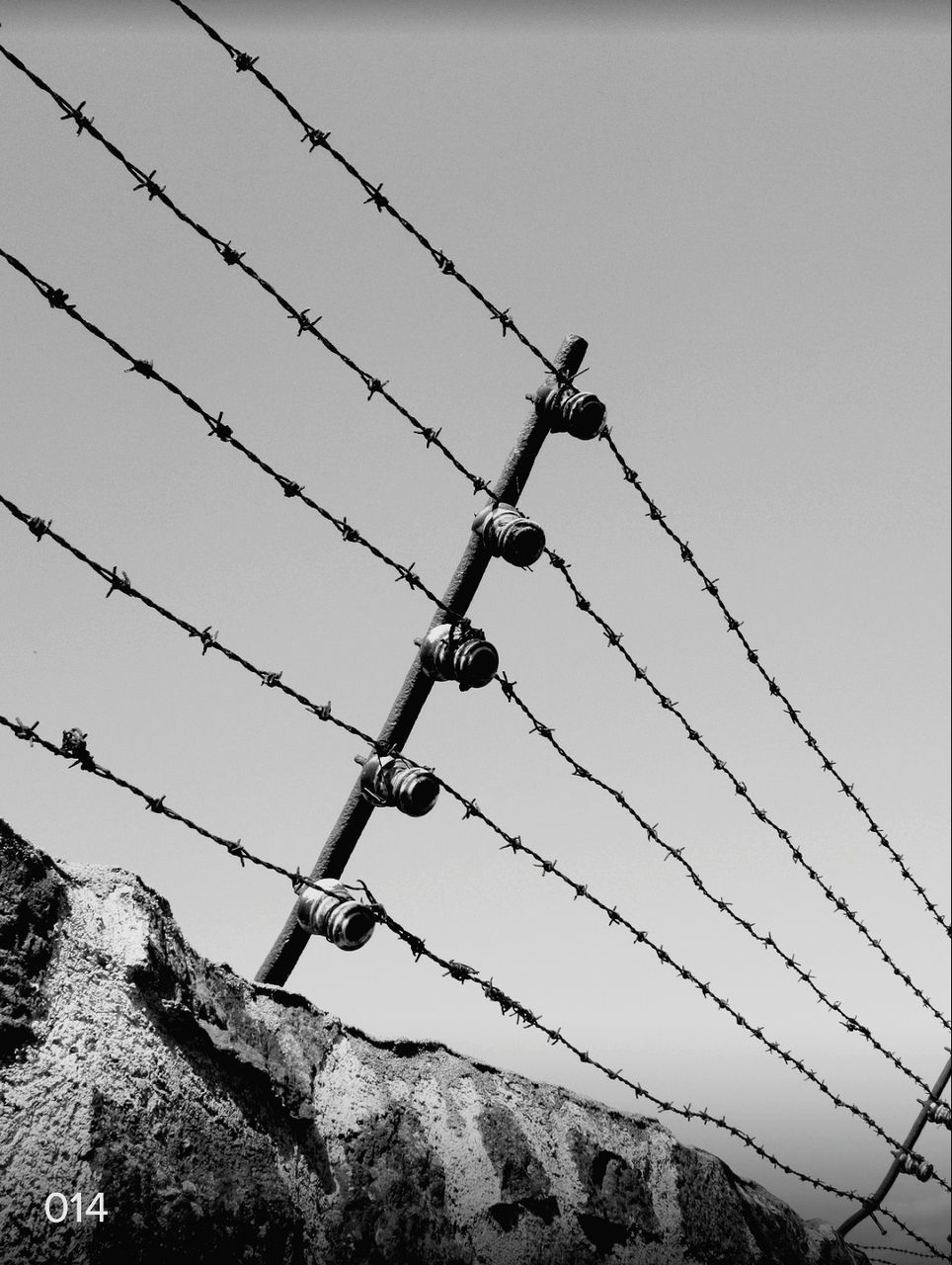 sky, low angle view, fence, barbed wire, no people, barrier, wire, boundary, clear sky, safety, day, protection, metal, nature, security, outdoors, close-up, mountain, rock, warning sign