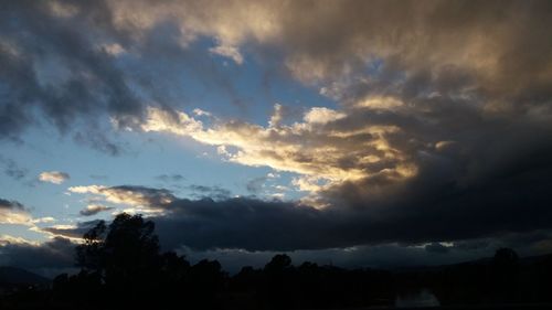 Low angle view of silhouette trees against dramatic sky