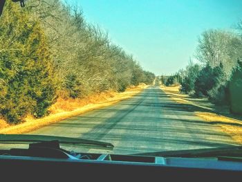 Road amidst trees against clear sky