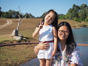 Portrait of smiling mother with cute daughter against landscape