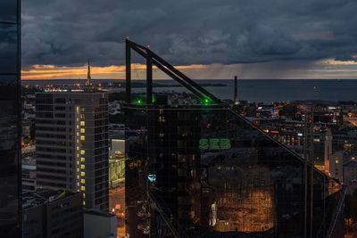 Illuminated buildings in city against sky at sunset