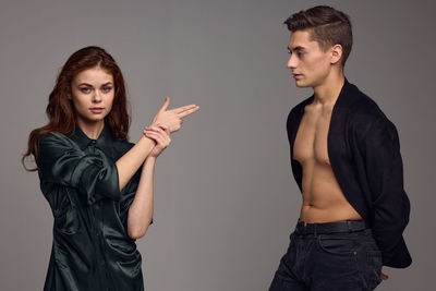 Young couple standing against gray background