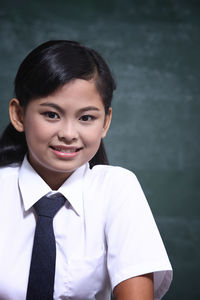 Portrait of girl in school uniform against blackboard