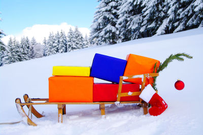 Multi colored christmas presents on sledge against clear blue sky