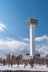 Gazebo in park by building against sky during winter