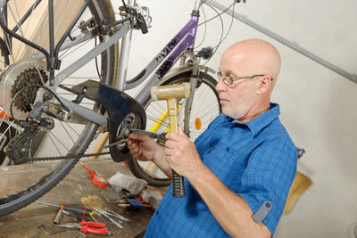 Mature man repairing bicycle in garage