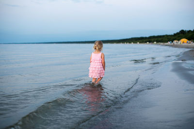 Girl wading in sea against sky