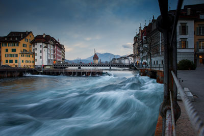 View of buildings at waterfront against cloudy sky