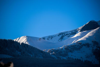 Scenic view of snowcapped mountains against clear blue sky