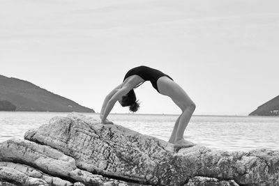 Full length of man on rock at beach against sky