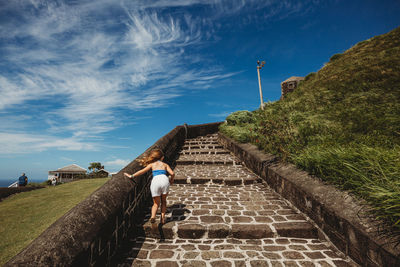 Rear view of woman walking on road against sky