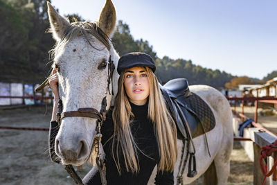 Portrait of young woman with horse in background