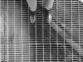 Low section of man standing in metal grate