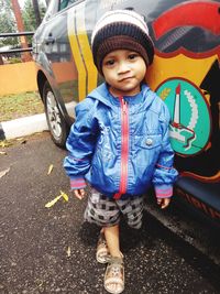 Portrait of cute boy standing by van outdoors