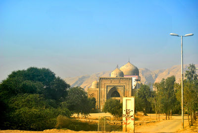 Old mosque by mountains against clear blue sky