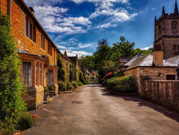 Footpath amidst buildings against sky