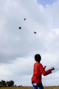 Rear view of boy flying against sky