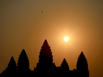 Silhouette temple against building during sunset